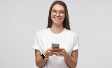 teenage girl wearing glasses, holding phone, smiling at camera