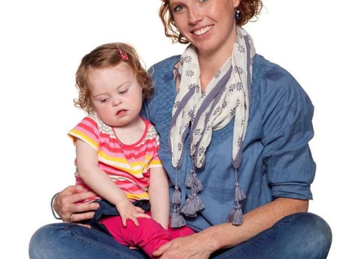mother with daughter in her lap (child has Down Syndrome)