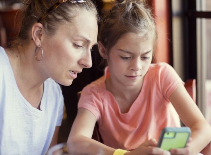 mother and tween daughter look at phone