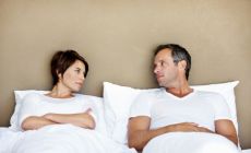 unhappy couple in bed looking at each other